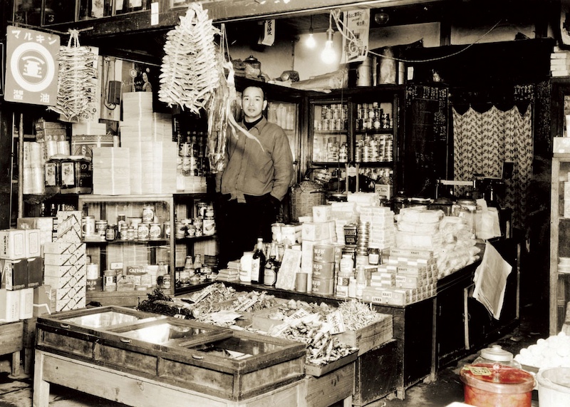昭和28年のふくや創業者・川原俊夫と食料品店「ふくや」店頭